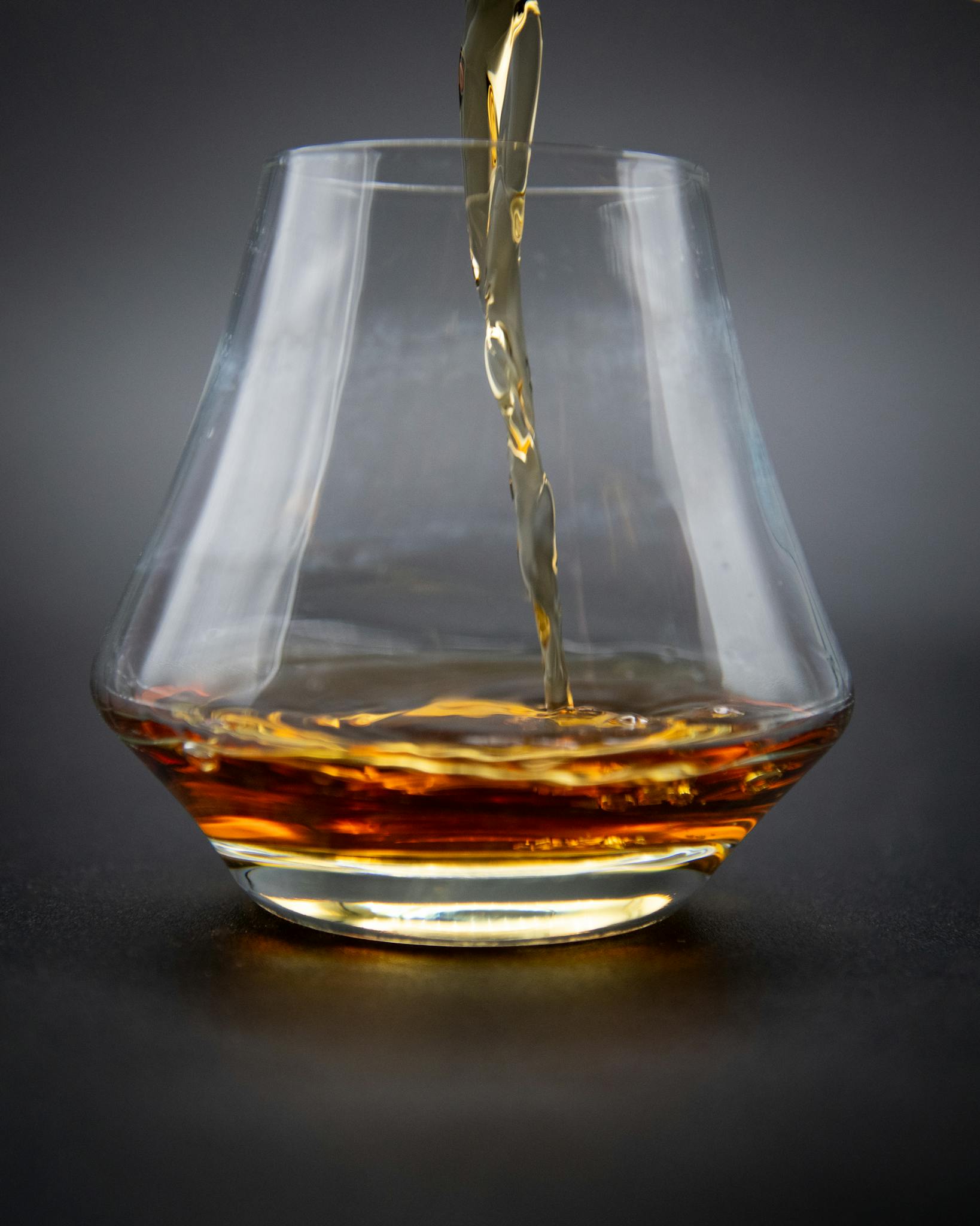 A close-up shot of whiskey being poured into a glass, showcasing rich amber hues.