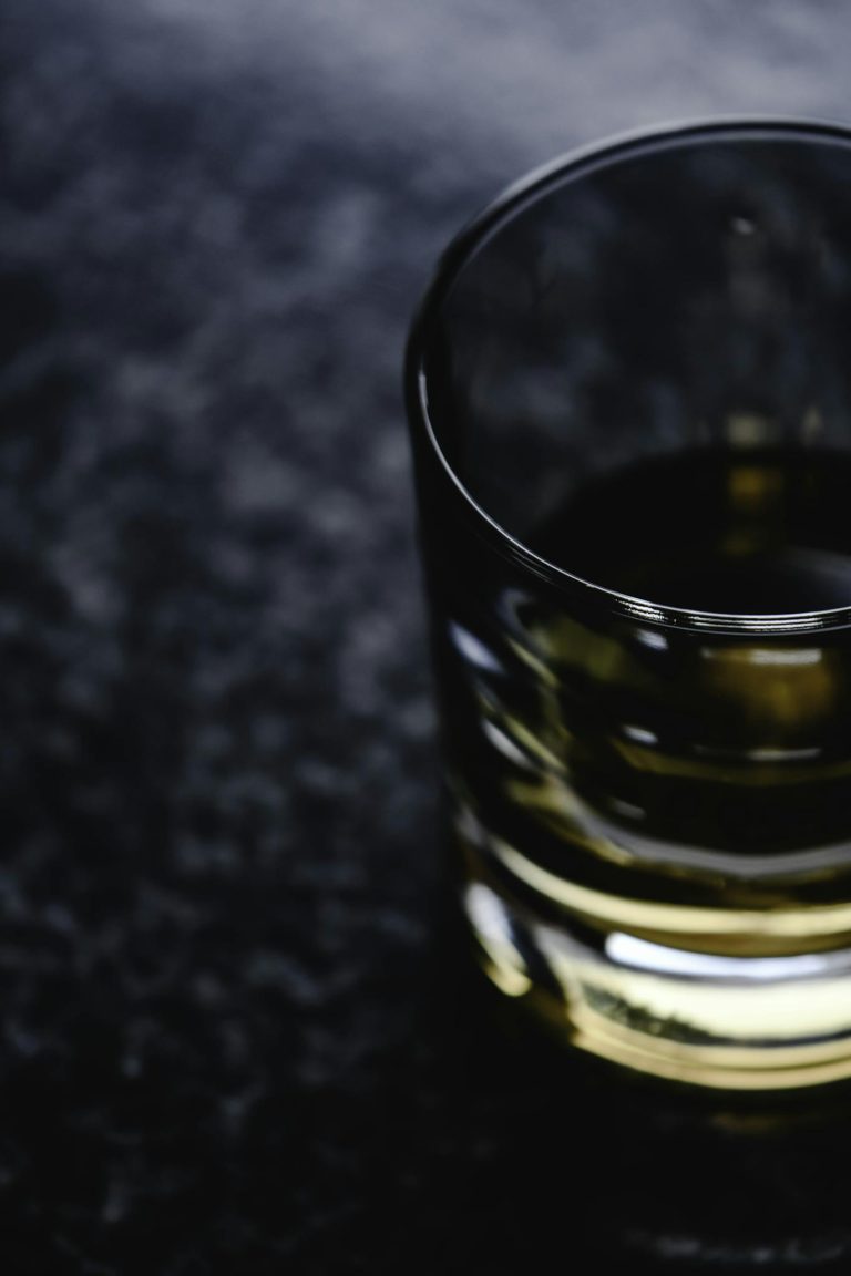 Top view of a whiskey glass on a textured dark surface, creating a moody ambiance.