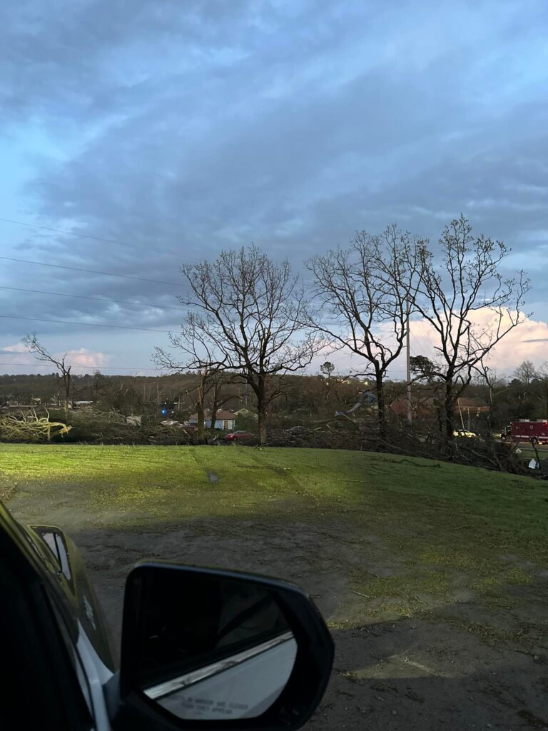 View of a storm-damaged landscape in North Little Rock, Arkansas, featuring fallen trees and debris, taken from inside a vehicle.