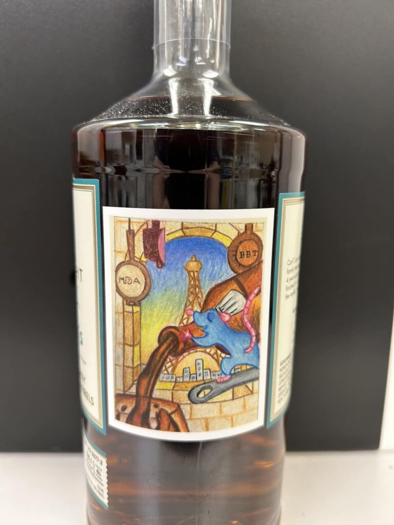 Glass bottle filled with dark brown liquor, featuring a colorful illustrated label showing a blue rat holding a pink bottle beside a brick wall and city skyline.