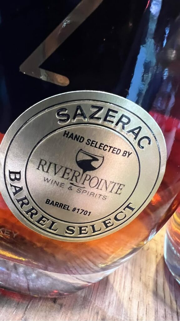 Close-up of a Sazerac Rye “Barrel Select” bottle label, hand selected by River Pointe Wine & Spirits, showing barrel #1701 and amber whiskey in the glass bottle.