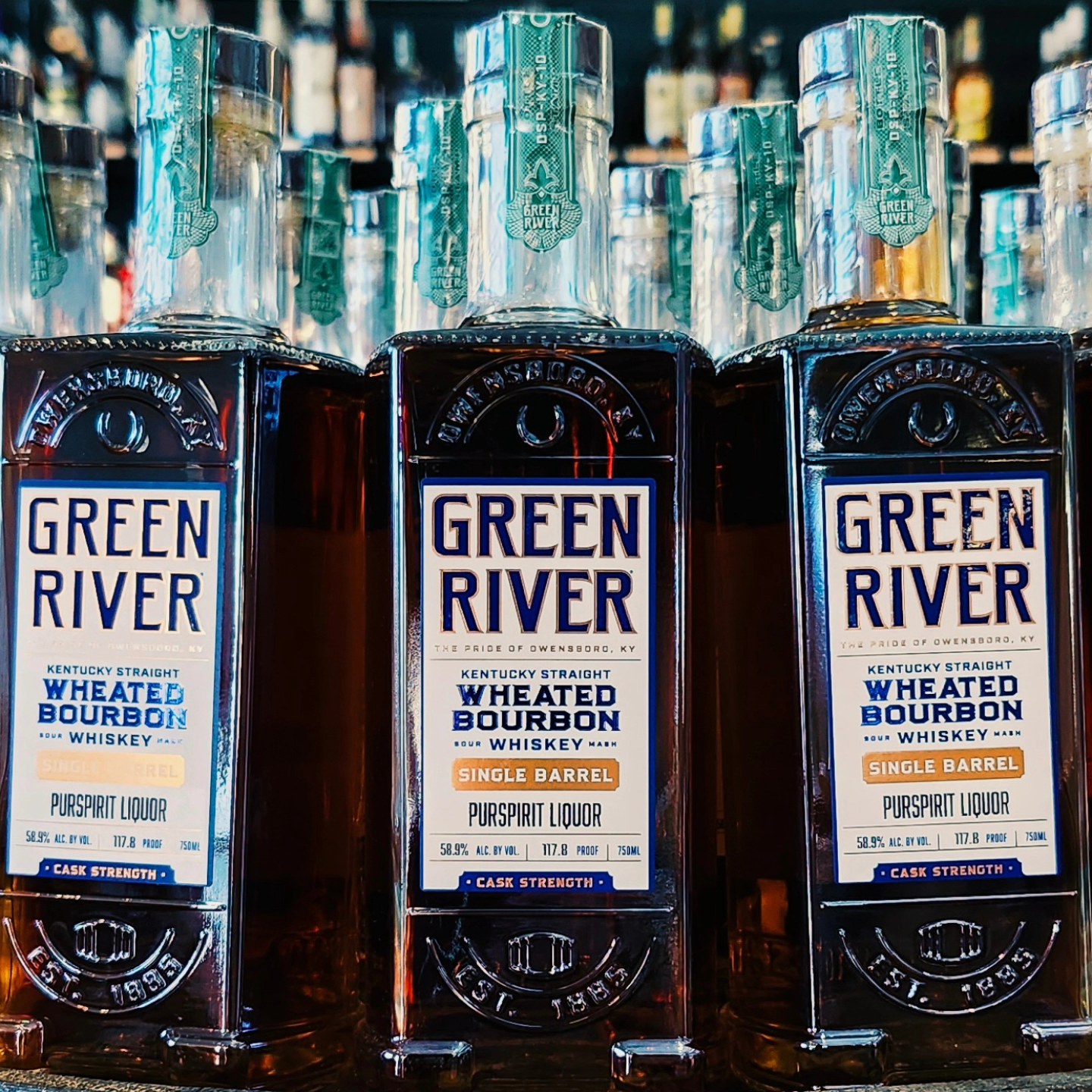 Close-up of Green River Kentucky Straight Wheated Bourbon whiskey bottles (single barrel, cask strength) lined up on a liquor store shelf.