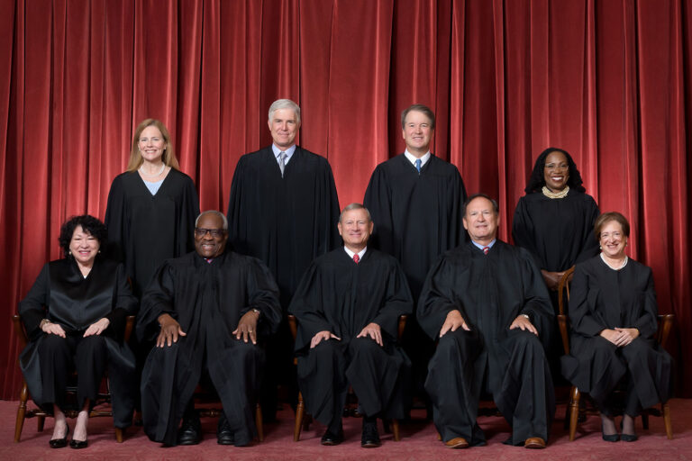 Formal group photograph of the Supreme Court as it was been comprised on June 30, 2022 after Justice Ketanji Brown Jackson joined the Court. The Justices are posed in front of red velvet drapes and arranged by seniority, with five seated and four standing. Seated from left are Justices Sonia Sotomayor, Clarence Thomas, Chief Justice John G. Roberts, Jr., and Justices Samuel A. Alito and Elena Kagan. Standing from left are Justices Amy Coney Barrett, Neil M. Gorsuch, Brett M. Kavanaugh, and Ketanji Brown Jackson. Credit: Fred Schilling, Collection of the Supreme Court of the United States