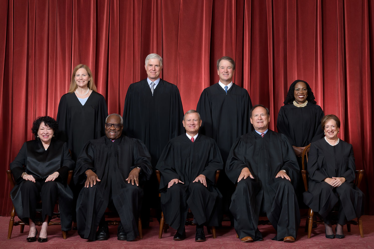 Formal group photograph of the Supreme Court as it was been comprised on June 30, 2022 after Justice Ketanji Brown Jackson joined the Court. The Justices are posed in front of red velvet drapes and arranged by seniority, with five seated and four standing. Seated from left are Justices Sonia Sotomayor, Clarence Thomas, Chief Justice John G. Roberts, Jr., and Justices Samuel A. Alito and Elena Kagan. Standing from left are Justices Amy Coney Barrett, Neil M. Gorsuch, Brett M. Kavanaugh, and Ketanji Brown Jackson. Credit: Fred Schilling, Collection of the Supreme Court of the United States